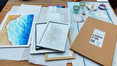 Kunstdruck, Bilderrahmen, Pappumschlag auf Tisch
