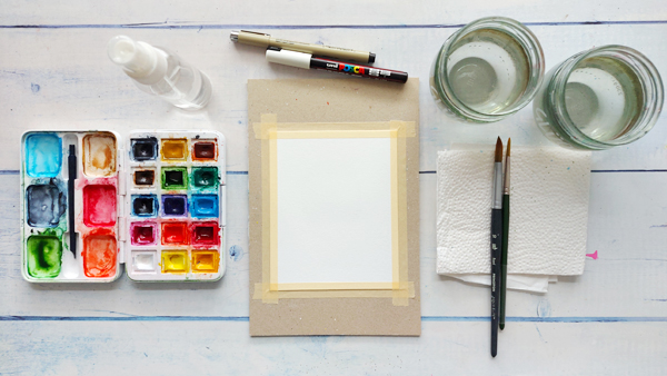 Aquarellmaterial wie Papier, Farbkasten und Pinsel auf Maltisch