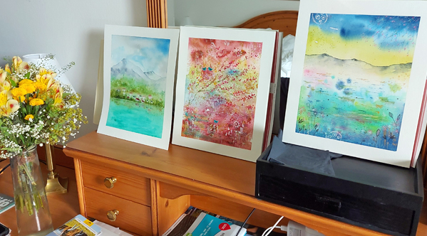 Drei Aquarell-Bilder aufgereiht auf einem Regalbrett