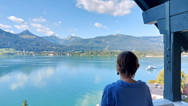 Frau blickt auf eine sommerliche Berg-See-Landschaft
