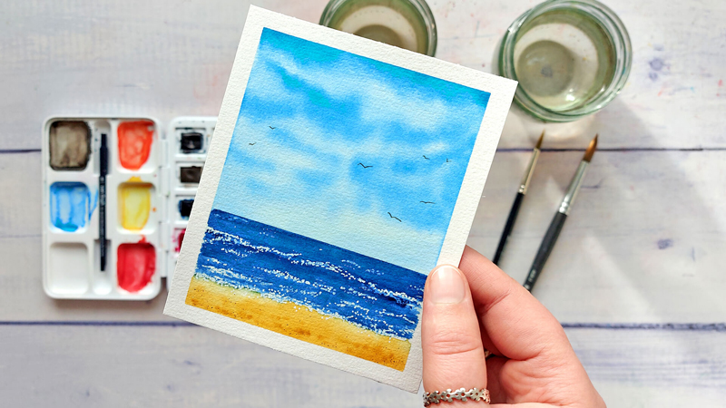 kleine Aquarell-Landschaft mit blauem Wolkenhimmel, Meer und Strand
