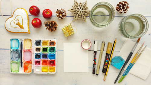 Malplatz mit Aquarellmaterial wie Farbkasten, Papier, Pinsel plus Weihnachtsdeko