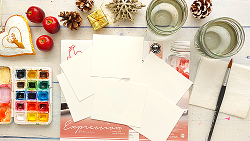 Weihnachtlich dekorierter Malplatz mit Aquarellpapierstücken