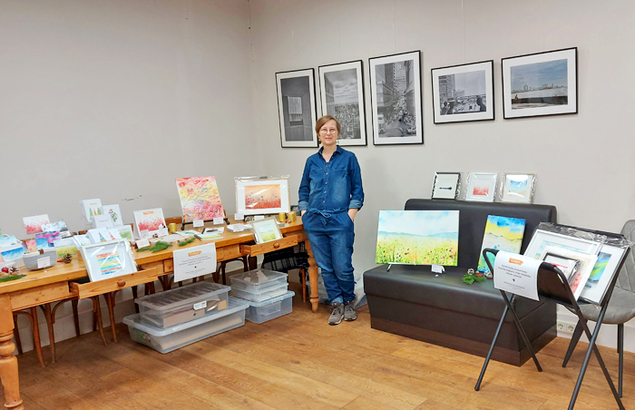 Franziska an ihrem Ausstellungsstand mit Aquarellbildern, Postkarten, Stickern, Leinwänden