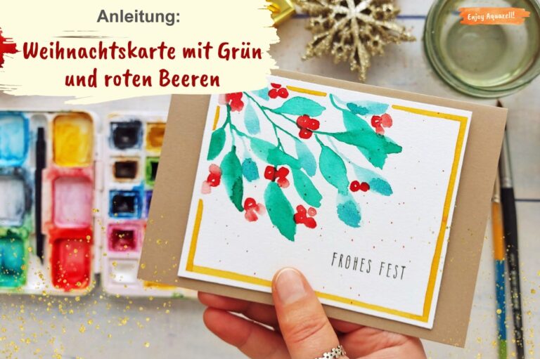 Hand hält Weihnachtskarte gemalt mit Aquarellfarben mit grünen Blättern und roten Beeren
