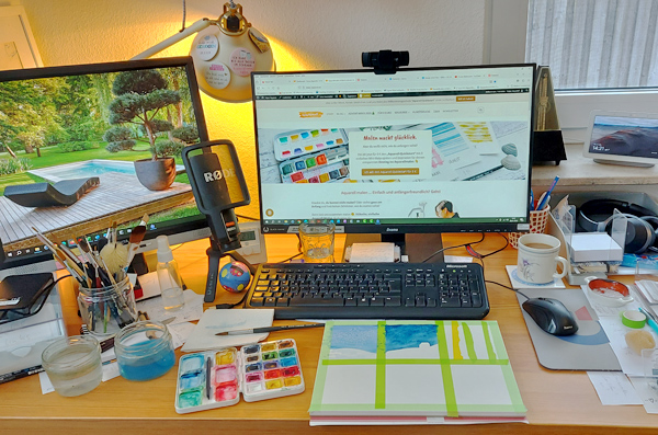 Schreibtisch mit Monitoren, Tastatur und Malsachen