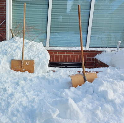 zwei Schneeschieber im Schnee