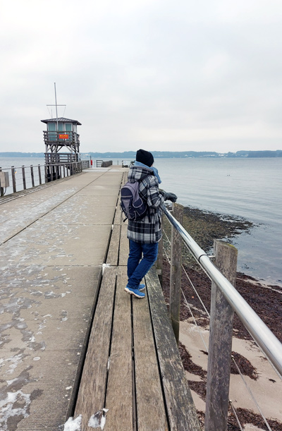 Frau auf Seebrücke in Winterkleidung