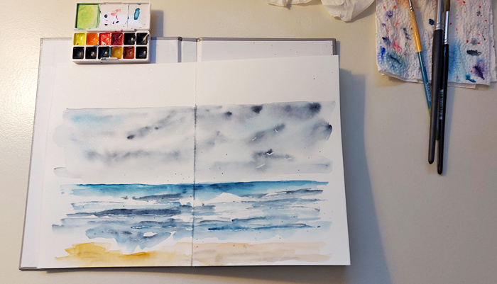 Reise-Skizzenbuch mit kleinem Farbkaste und Aquarellbild mit Motiv Meer und Himmel