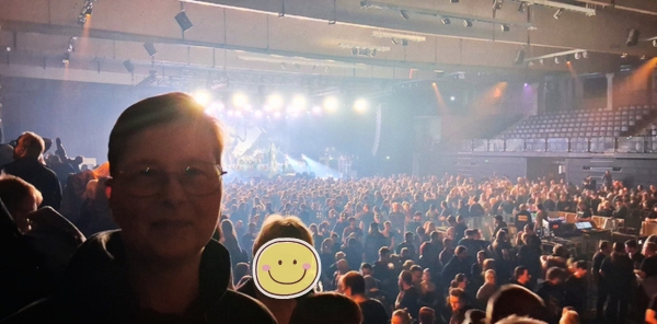 Frau in Konzerthalle im Hintergrund viele Menschen und die Bühne