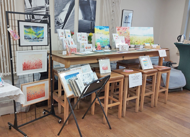 Stand auf Messe in Form eines hohen Holztisches fertig aufgebaut mit Kunstdrucken und Grußkarten