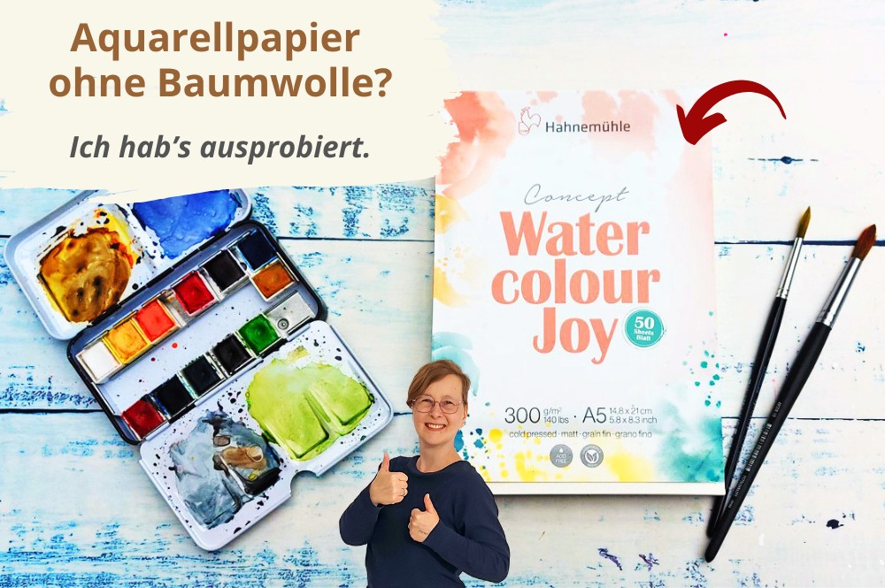 Malplatz mit Aquarellfarbkasten, Papierblock, zwei Pinseln und Frau mit zwei Daumen hoch