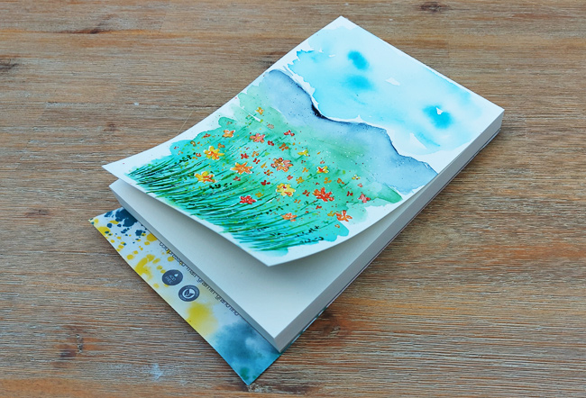 Bemaltes und stark gewelltes oberstes Blatt an einem Aquarellblock