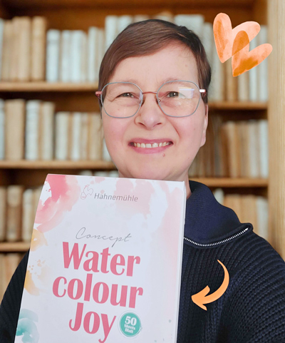 Frau mit Aquarellblock vor Bücherregal