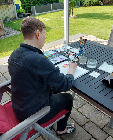 Frau malt am Tisch im Garten