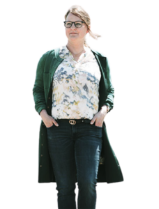 Freundlich lächelnde Frau mit Brille, langen Haaren und grüner Jacke