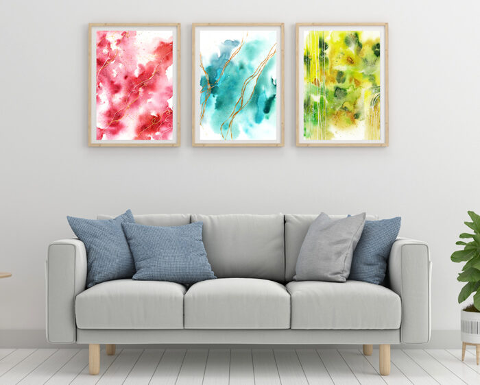 Drei abstrakte Aquarellbilder in Rot, Blau, Grn über grauem Sofa