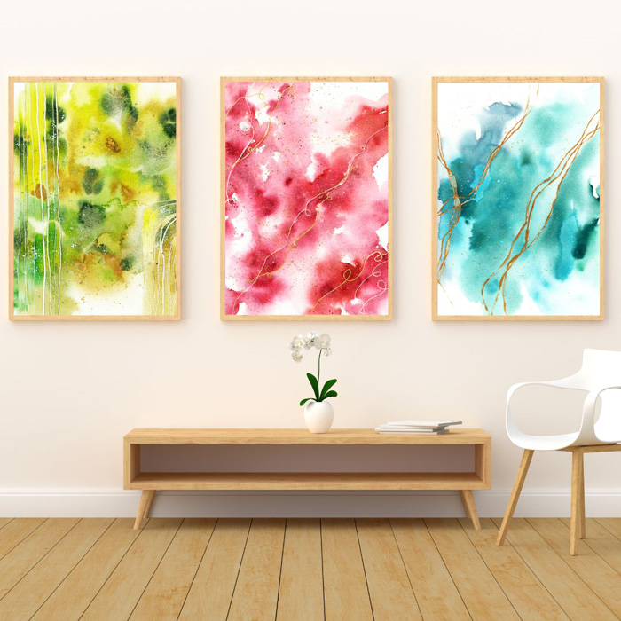 Drei abstrakte Aquarelle in grün, rot und blau über flachem Holzwandtisch