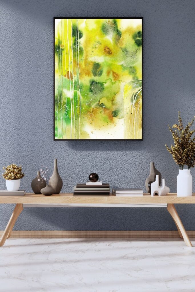 Abstraktes Aquarellbild in Grüntönen an grauer Wand über Holztisch
