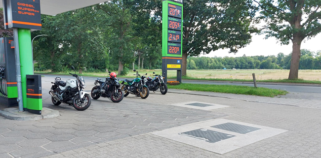 vier Motorräder an einer Tankstelle