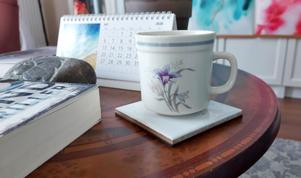 Kaffeebecher auf weißem Untersetzer auf braunem Tisch