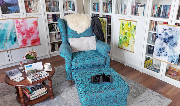 Blauer Lesesessel vor Bücherregal mit kleinem Tischchen