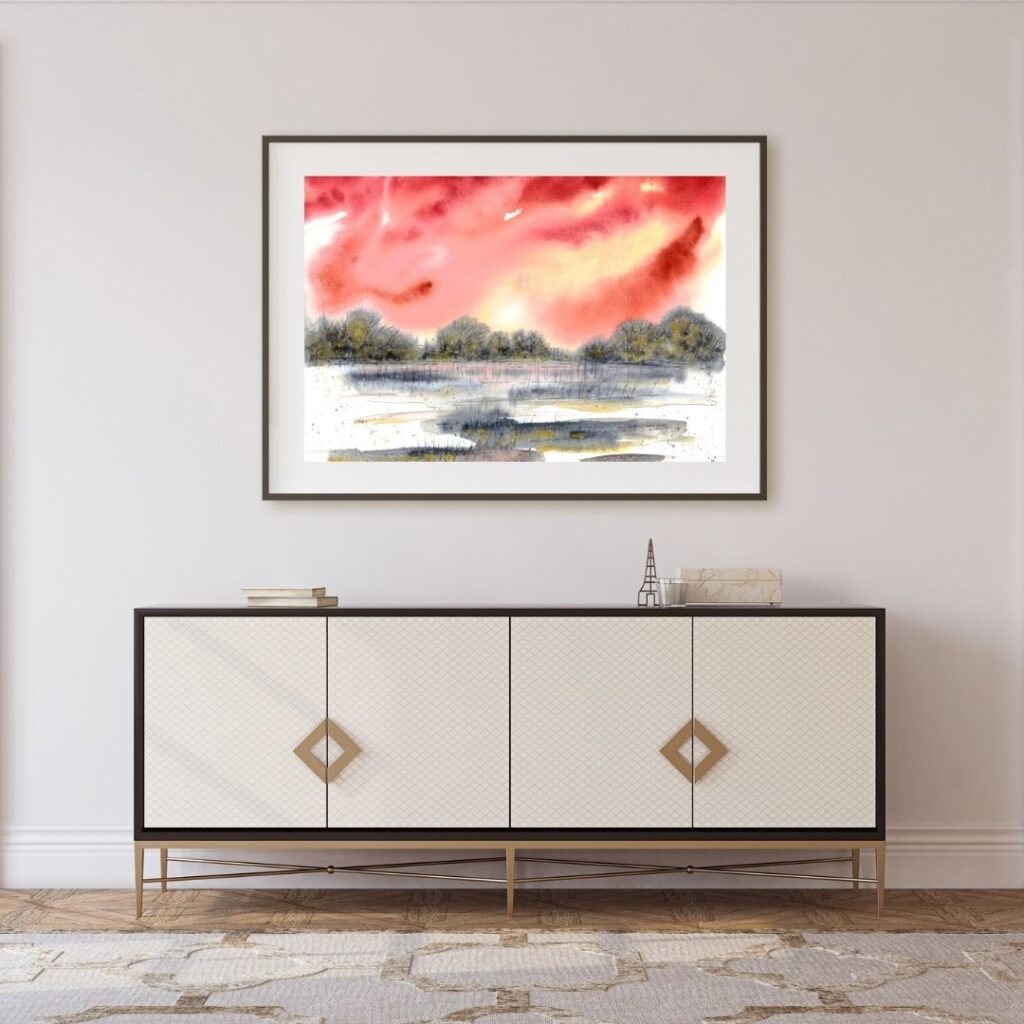 Aquarell halb abstrakt mit rotem Himmel und grau-goldener Landschaft über hellem Sideboard