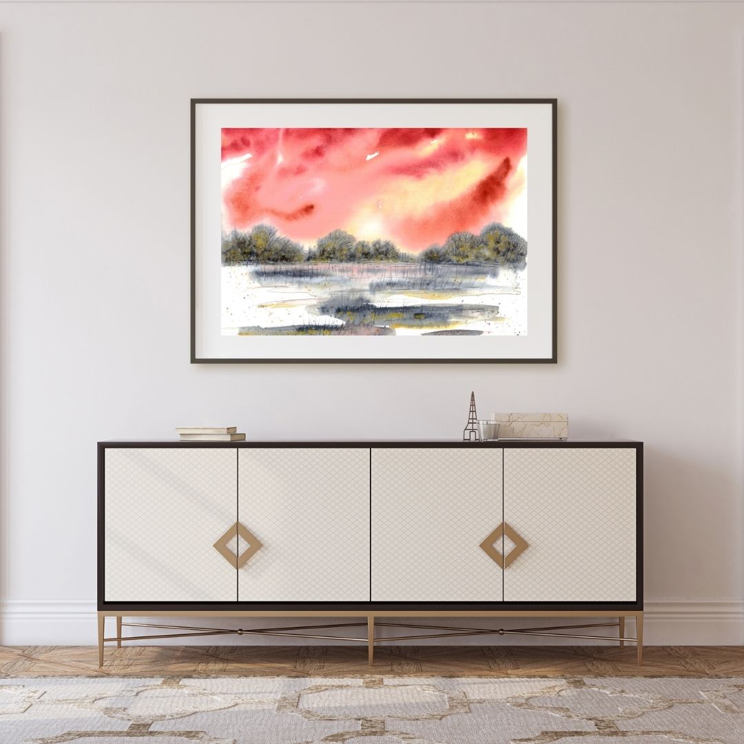 Aquarell halb abstrakt mit rotem Himmel und grau-goldener Landschaft über hellem Sideboard